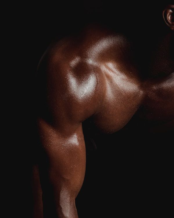 Man performing a controlled strength exercise in a dark gym.